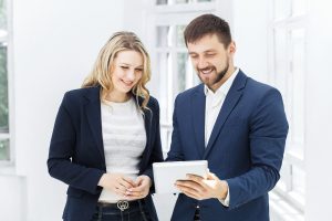 The smiling male and female office workers with laptop